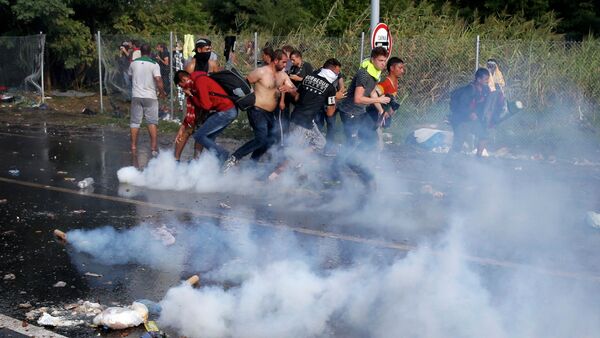 Migrants protest as Hungarian riot police fires tear gas and water cannon at the border crossing with Serbia in Roszke, Hungary September 16, 2015 - Sputnik International