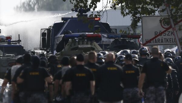 Hungarian riot policemen fire a water cannon as migrants protest on the Serbian side of the border crossing in Roszke, Hungary September 16, 2015 - Sputnik International