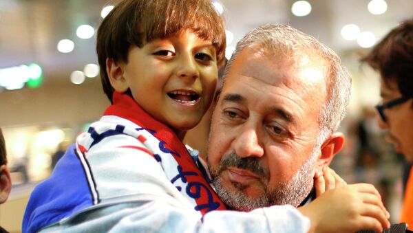 Syrian Osama Abdul Mohsen holds his son Zaid as they arrive at the Barcelona train station on September 16. - Sputnik International