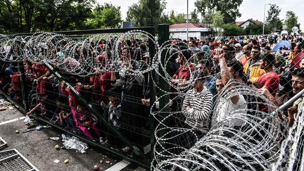 Refugees stand behind a fence at the Hungarian border with Serbia near the town of Horgos on September 16, 2015 - Sputnik International