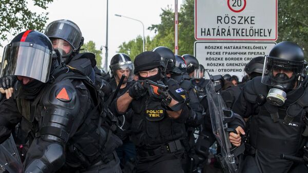 Hungarian riot police fight migrants at the border crossing with Serbia in Roszke, Hungary September 16, 2015 - Sputnik International