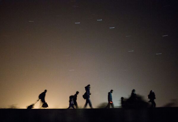 Migrants walk towards a checkpoint along the railway tracks connecting Horgos and Szeged near Roszke, in the vicinity of the border between Hungary and Serbia Migrants walk towards a checkpoint along the railway tracks connecting Horgos and Szeged near Roszke, in the vicinity of the border between Hungary and Serbia - Sputnik International