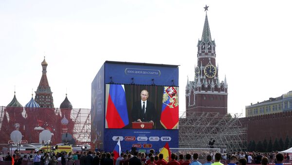 Officials, participants of a soccer exhibition under-16 tournament and spectators listen to Russia's President Vladimir Putin delivering a speech via a video link from Sochi, during a ceremony marking 1,000 days until the beginning of the 2018 FIFA World Cup in Red Square in central Moscow, Russia, September 18, 2015 - Sputnik International