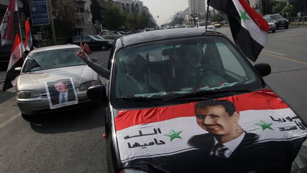 Syrians display national flags and banners with photos of Syrian President Bashar Assad. - Sputnik International