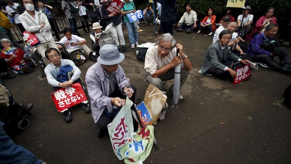 Protesters sitting on the ground with placards take part in a rally against Japan's Prime Minister Shinzo Abe's security bill and his administration in front of the parliament in Tokyo, September 18, 2015. - Sputnik International