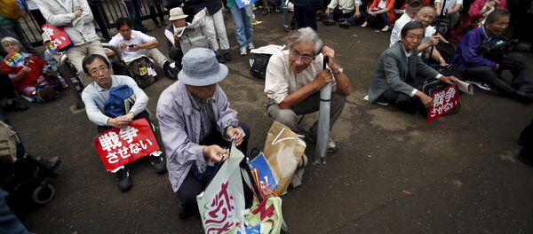 Protesters sitting on the ground with placards take part in a rally against Japan's Prime Minister Shinzo Abe's security bill and his administration in front of the parliament in Tokyo, September 18, 2015. - Sputnik International