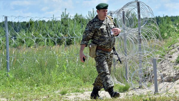 A Ukrainian border guard patrols on July 2, 2015 along the barbed wire fence on the Senkivka border post - Sputnik International