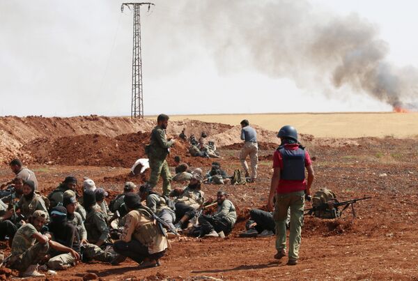 An unidentified photographer stands next to rebel fighters from Jaysh al-Islam (Army of Islam) holding a position behind a sand barrier on August 25, 2015, on the frontline in the Bashkoy area, on the northern outskirts of Aleppo, where opposition fighters are battling Syrian pro-government forces An unidentified photographer stands next to rebel fighters from Jaysh al-Islam (Army of Islam) holding a position behind a sand barrier on August 25, 2015, on the frontline in the Bashkoy area, on the northern outskirts of Aleppo, where opposition fighters are battling Syrian pro-government forces - Sputnik International