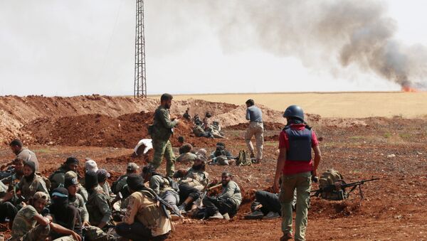 An unidentified photographer stands next to rebel fighters from Jaysh al-Islam (Army of Islam) holding a position behind a sand barrier on August 25, 2015, on the frontline in the Bashkoy area, on the northern outskirts of Aleppo, where opposition fighters are battling Syrian pro-government forces - Sputnik International
