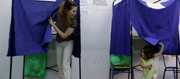 A woman casts her vote as her three-year old daughter plays in an election booth at a polling station in Athens, Sunday, Sept. 20, 2015 - Sputnik International