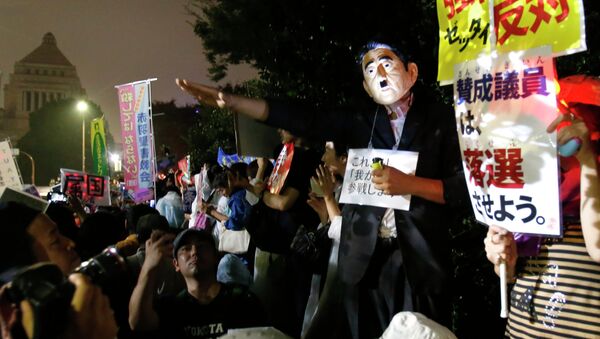A protester wearing a mask of Japanese Prime Minister Shinzo Abe gestures during a rally against Japanese government in front of the parliament building in Tokyo, Friday, Sept. 18, 2015 - Sputnik International