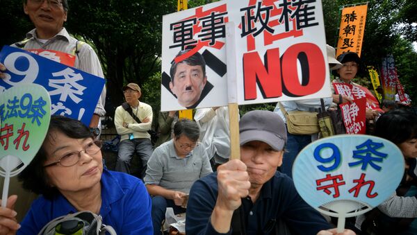 Demonstrators hold placards to protest against Prime Minister Shinzo Abe's controversial security bills in front of the National Diet in Tokyo on September 18, 2015 - Sputnik International