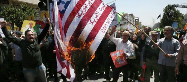 Iranian demonstrators burn a representation of the U.S. flag reading down with America, in Arabic and Persian, during an annual pro-Palestinian rally marking Al-Quds (Jerusalem) Day at the Enqelab-e-Eslami (Islamic Revolution) St. in Tehran, Iran, Friday, July 10, 2015 - Sputnik International