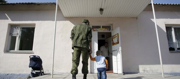 A man wearing a camouflage uniform walks with a child as they enter a school on the start of the new school year in Donetsk, Ukraine, September 1, 2015 A man wearing a camouflage uniform walks with a child as they enter a school on the start of the new school year in Donetsk, Ukraine, September 1, 2015 - Sputnik International