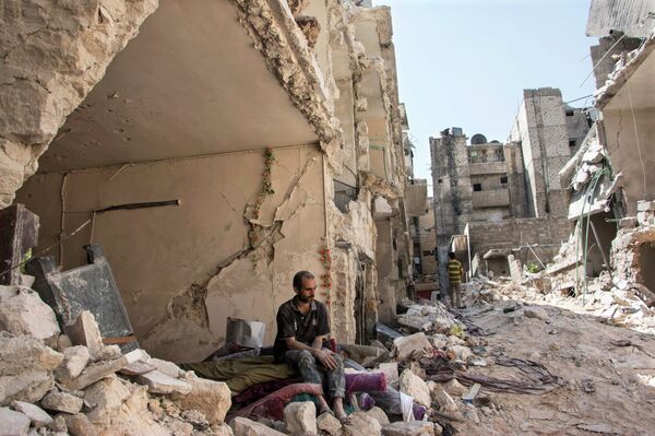 A Syrian man sits in the rubble following a barrel bomb attack the previous day on the rebel-held neighbourhood of al-Mashad in the northern Syrian city of Aleppo on September 17, 2015 A Syrian man sits in the rubble following a barrel bomb attack the previous day on the rebel-held neighbourhood of al-Mashad in the northern Syrian city of Aleppo on September 17, 2015 - Sputnik International