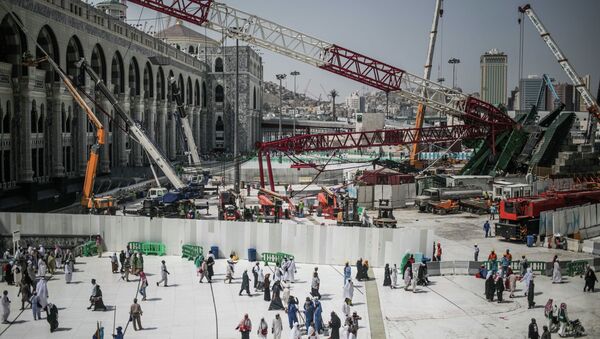 Muslim Pilgrims walk past the site of a crane collapse that killed over a hundred Friday at the Grand Mosque in the holy city of Mecca, Saudi Arabia, Tuesday, Sept. 15, 2015. - Sputnik International