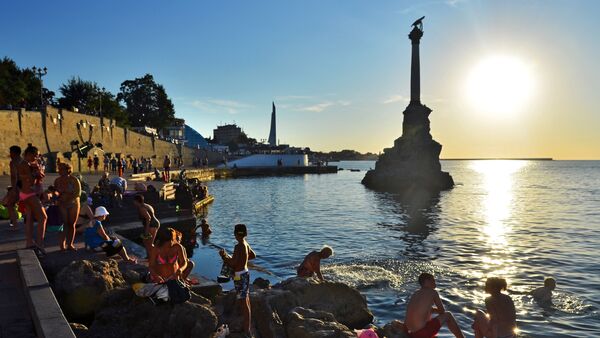 Holidaymakers and local residents bathe at dusk near a monument to sunken ships in Sevastopol - Sputnik International