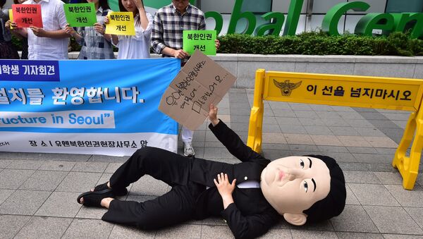 A South Korean activist wearing a mask depicting North Korean leader Kim Jong-Un lies on a street during a rally to welcome the opening of the UN Human Rights office at Seoul Global Center in Seoul on June 23, 2015 - Sputnik International