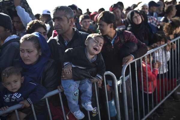 A Syrian refugee man holding his sleeping son, rests on the ground after spending the night at a collection point in the truck parking lot of the former border station on the Austrian side of the Hungarian-Austrian border near Nickelsdorf, Austria, Wednesday, Sept. 23, 2015. A Syrian refugee man holding his sleeping son, rests on the ground after spending the night at a collection point in the truck parking lot of the former border station on the Austrian side of the Hungarian-Austrian border near Nickelsdorf, Austria, Wednesday, Sept. 23, 2015. - Sputnik International