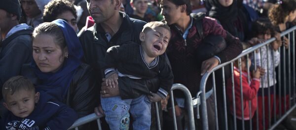 A Syrian refugee man holding his sleeping son, rests on the ground after spending the night at a collection point in the truck parking lot of the former border station on the Austrian side of the Hungarian-Austrian border near Nickelsdorf, Austria, Wednesday, Sept. 23, 2015. A Syrian refugee man holding his sleeping son, rests on the ground after spending the night at a collection point in the truck parking lot of the former border station on the Austrian side of the Hungarian-Austrian border near Nickelsdorf, Austria, Wednesday, Sept. 23, 2015. - Sputnik International