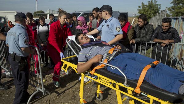 A migrant is carried on a stretcher after he collapsed in front of a registration camp in Opatovac, Croatia September 23, 2015. - Sputnik International