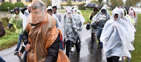 Refugees walked in heavy rain from a public transport centre to Lappia-building refugee reception centre in Tornio, northwestern Finland - Sputnik International