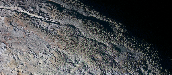 Rounded and bizarrely textured mountains, informally named the Tartarus Dorsa, rise up along Pluto’s day-night terminator and show intricate but puzzling patterns of blue-gray ridges and reddish material in between. - Sputnik International
