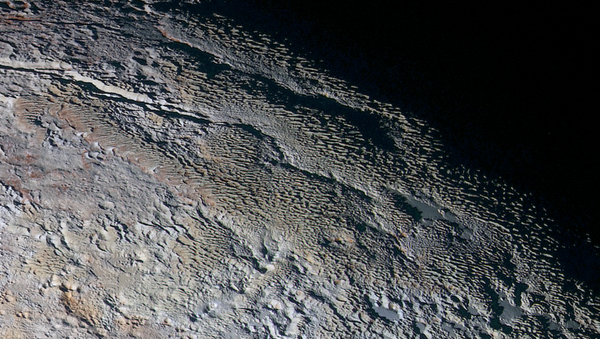 Rounded and bizarrely textured mountains, informally named the Tartarus Dorsa, rise up along Pluto’s day-night terminator and show intricate but puzzling patterns of blue-gray ridges and reddish material in between. - Sputnik International