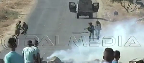 A military vehicle chases down Bernardi, who, knelt at right, attempts to pick up his camera. - Sputnik International