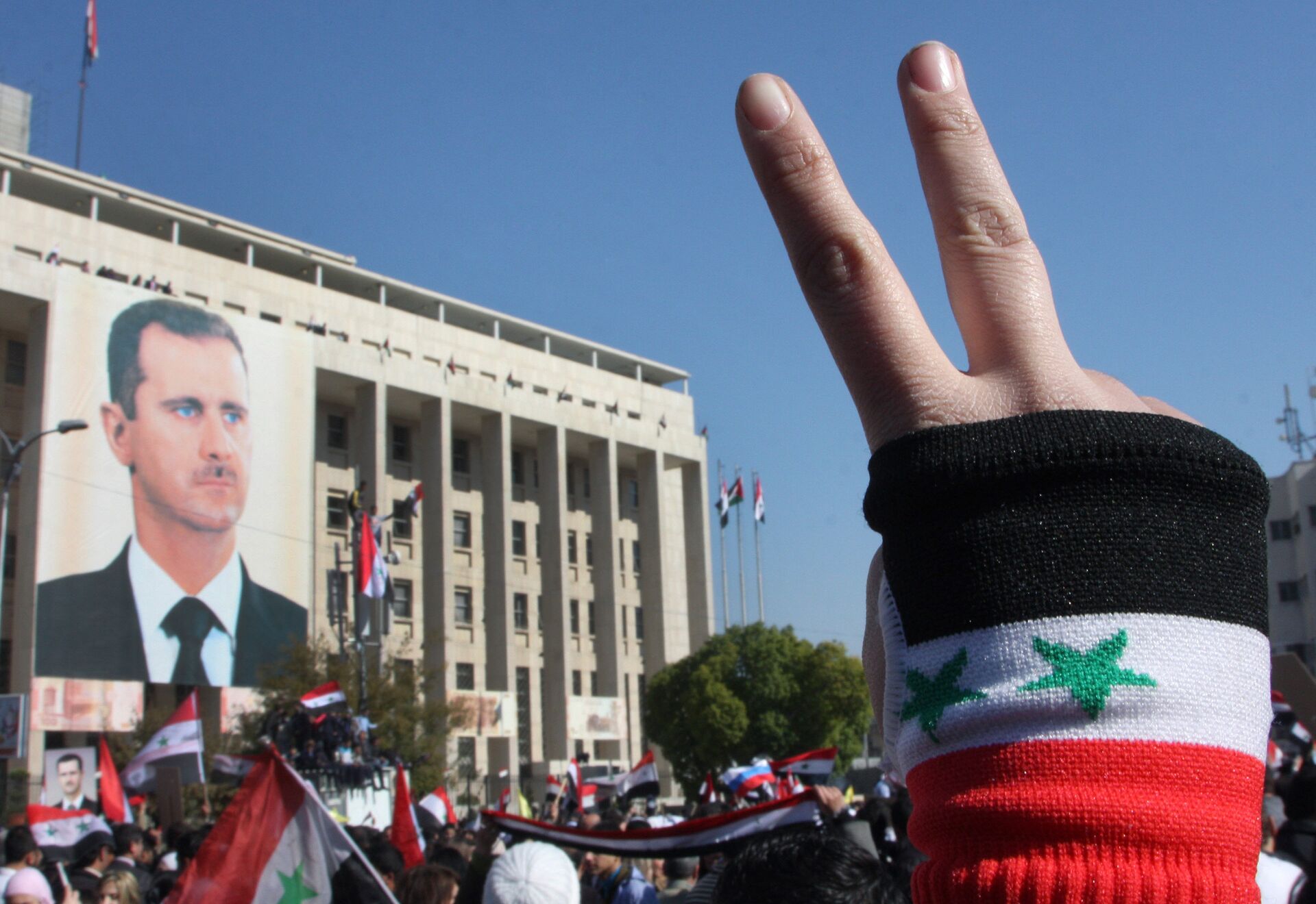 A pro-Syrian regime protester flashes V-victory sign - Sputnik International, 1920, 26.11.2021