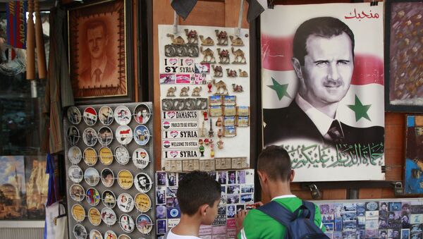 Syrian students, look for souvenir items at a shop displaying a portrait of Syrian President Bashar Assad with Arabic legend reads We love you, in the old city of Damascus, Syria - Sputnik International