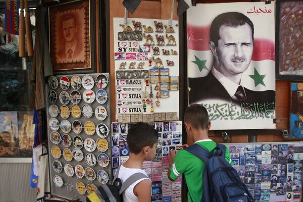 Syrian students, look for souvenir items at a shop displaying a portrait of Syrian President Bashar Assad with Arabic legend reads We love you, in the old city of Damascus, Syria Syrian students, look for souvenir items at a shop displaying a portrait of Syrian President Bashar Assad with Arabic legend reads We love you, in the old city of Damascus, Syria - Sputnik International