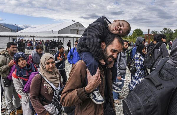 Migrants and refugees stand in line as they wait to board a train at the registration camp after crossing the Macedonian-Greek border near Gevgelija on September 28, 2015 - Sputnik International