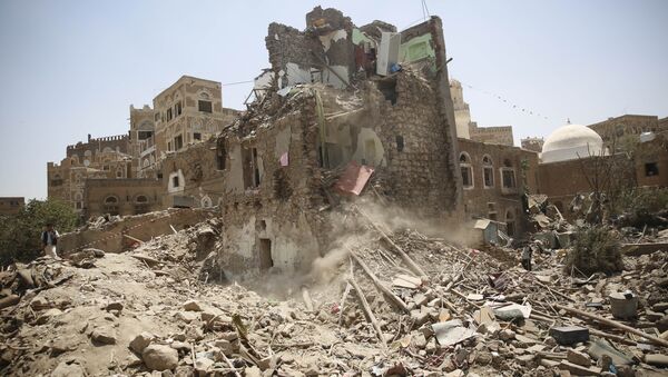 A man, left, stands guard amid the rubble of a house damaged in a Saudi-led airstrike in Sanaa, Yemen, Saturday, Sept. 19, 2015. - Sputnik International
