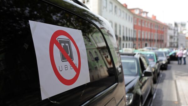 Taxis with signs against the Uber ride-hailing service clog a street in Lisbon while moving at a slow pace in protest, Tuesday, Sept. 8 2015 - Sputnik International