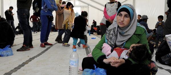 A migrant woman holds a baby inside a large tent set by NGOs, as refugees and migrants wait to cross Greece's border with Macedonia near the Greek village of Idomeni, September 26, 2015 A migrant woman holds a baby inside a large tent set by NGOs, as refugees and migrants wait to cross Greece's border with Macedonia near the Greek village of Idomeni, September 26, 2015 - Sputnik International