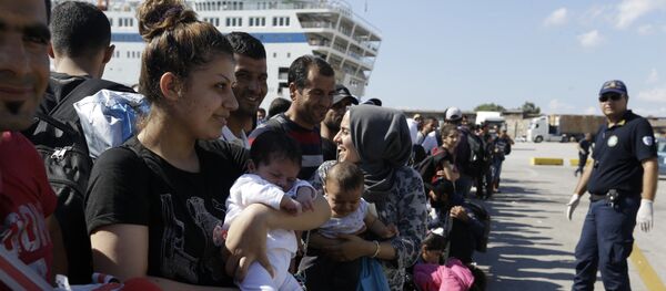Syrian mother, left, holds her one-month old daughter as she waits for the bus transporting them to the metro station after their arrival from the Greek island of Lesbos at the Athens' port of Piraeus, Monday, Sept. 28, 2015 - Sputnik International