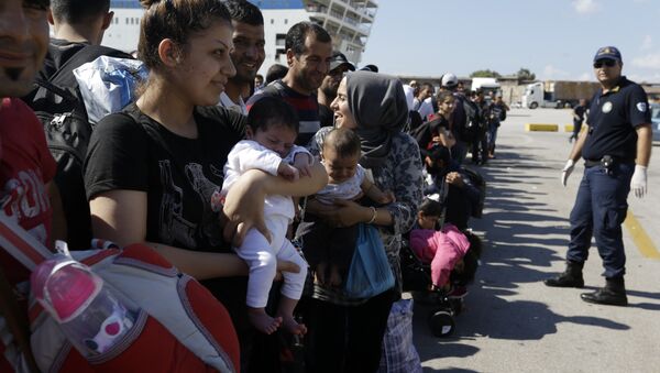Syrian mother, left, holds her one-month old daughter as she waits for the bus transporting them to the metro station after their arrival from the Greek island of Lesbos at the Athens' port of Piraeus, Monday, Sept. 28, 2015 - Sputnik International