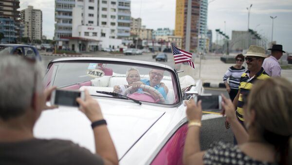 U.S. citizens pose for photos as they enjoy a ride in a vintage car at the seafront Malecon during a cultural exchange trip in Havana, September 28, 2015 - Sputnik International