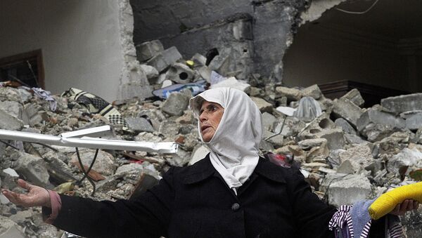 In this Wednesday, Feb. 6, 2013 photo, a Syrian woman stands amid the ruins of her house which was destroyed in an airstrike by government warplanes a few days earlier, killing 11 members of her family, in the neighborhood of Ansari, Aleppo, Syria. - Sputnik International