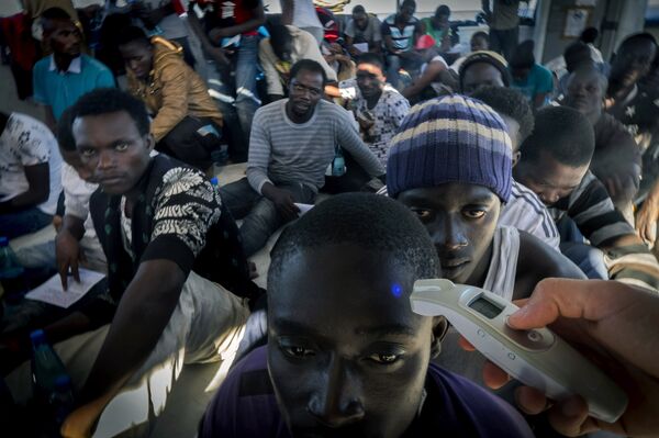 A member of Medecins Sans Frontieres (Doctors without borders - MSF) checks the temperature of a refugee onboard the Dignity 1 search and rescue vessel after they were rescued along with other migrants from their rubber boat by members of MSF in the Meditterranean sea off the coast of Libya on September 29, 2015 A member of Medecins Sans Frontieres (Doctors without borders - MSF) checks the temperature of a refugee onboard the Dignity 1 search and rescue vessel after they were rescued along with other migrants from their rubber boat by members of MSF in the Meditterranean sea off the coast of Libya on September 29, 2015 - Sputnik International
