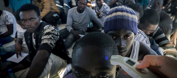 A member of Medecins Sans Frontieres (Doctors without borders - MSF) checks the temperature of a refugee onboard the Dignity 1 search and rescue vessel after they were rescued along with other migrants from their rubber boat by members of MSF in the Meditterranean sea off the coast of Libya on September 29, 2015 A member of Medecins Sans Frontieres (Doctors without borders - MSF) checks the temperature of a refugee onboard the Dignity 1 search and rescue vessel after they were rescued along with other migrants from their rubber boat by members of MSF in the Meditterranean sea off the coast of Libya on September 29, 2015 - Sputnik International