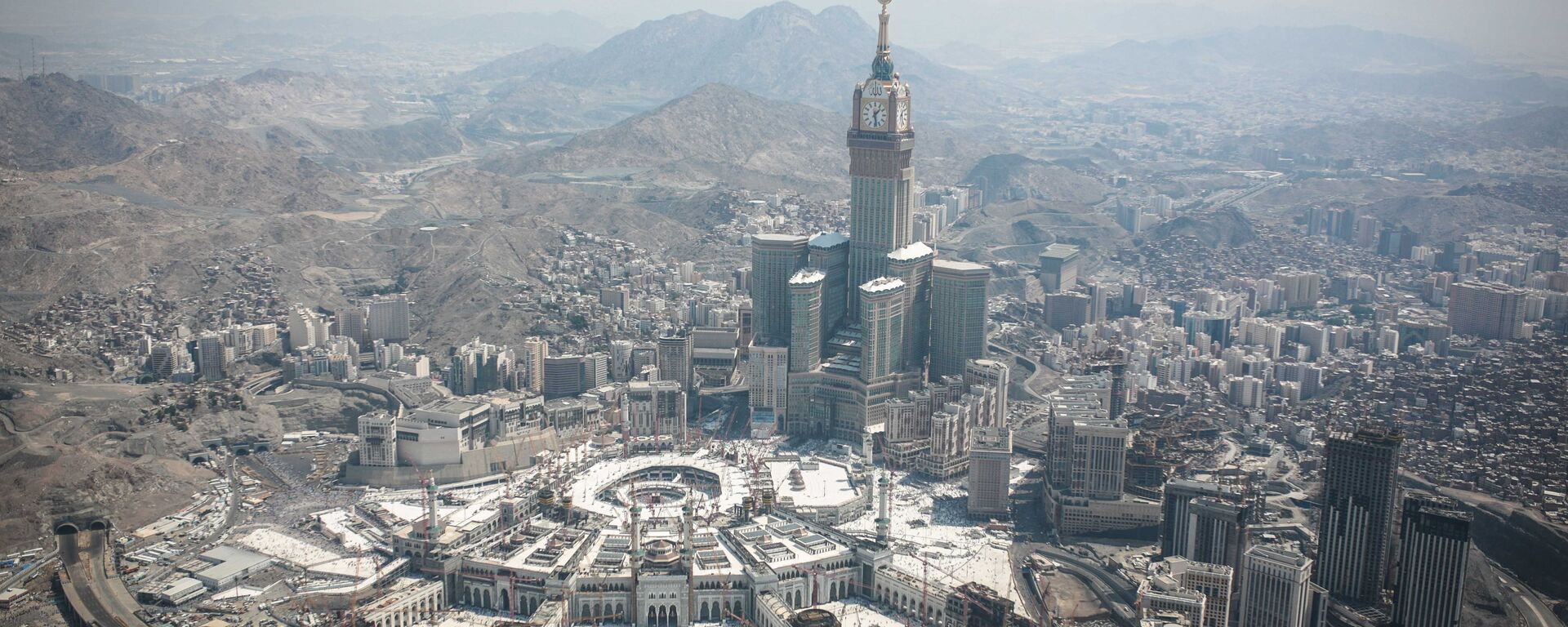 In this aerial photo made from a helicopter, the Abraj Al-Bait Towers with the four-faced clocks stands over the holy Kaaba, as Muslims encircle it inside the Grand Mosque, during the annual pilgrimage known as the hajj, in the Muslim holy city of Mecca, Saudi Arabia, Friday, Sept. 25, 2015. - Sputnik International, 1920, 18.06.2024