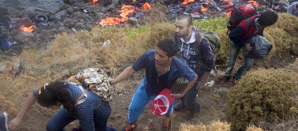 Syrian refugees climb a slope after arriving on an overcrowded dinghy under heavy rainfall on the Greek island of Lesbos after crossing a part of the Aegean Sea from the Turkish coast, September 28, 2015 Syrian refugees climb a slope after arriving on an overcrowded dinghy under heavy rainfall on the Greek island of Lesbos after crossing a part of the Aegean Sea from the Turkish coast, September 28, 2015 - Sputnik International