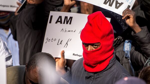 A migrant holds a placard reading 'I am Ahmed. Go to UK' - Sputnik International