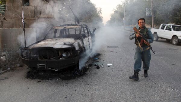 An Afghan policeman patrols next to a burning vehicle in the city of Kunduz, Afghanistan October 1, 2015 - Sputnik International