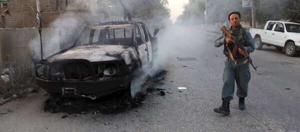 An Afghan policeman patrols next to a burning vehicle in the city of Kunduz, Afghanistan October 1, 2015 - Sputnik International