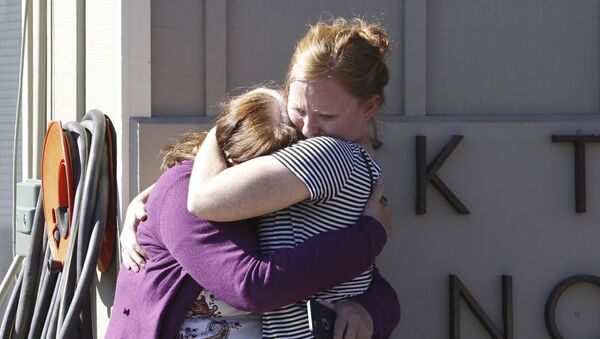 Umpqua Community College alumnus Donice Smith (L) is embraced after she said one of her former teachers was shot dead, near the site of a mass shooting at Umpqua Community College in Roseburg,Oregon October 1, 2015 - Sputnik International
