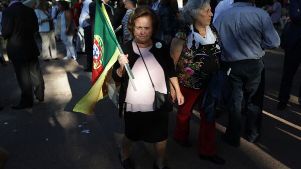 A supporter of the Portuguese Socialist Party carries a Portuguese flag while waiting for the arrival of the party leader Antonio Costa during a campaign action in Lisbon Tuesday, Sept. 29 2015. - Sputnik International
