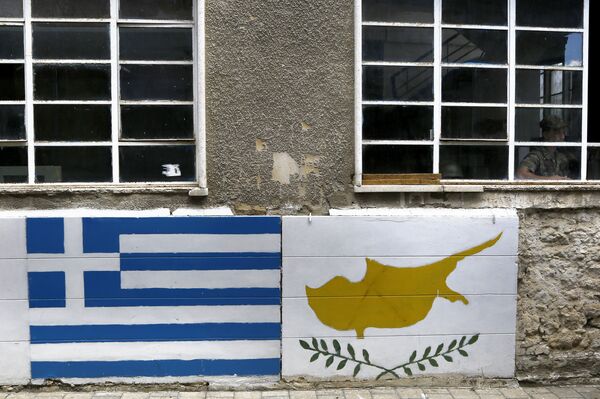 A representation of the Greek, left, and Cyprus flags are painted on a wall as a Greek Cypriot soldier is seen inside a guard post by the U.N controlled buffer zone as they cuts across the Cypriot divided capital Nicosia - Sputnik International